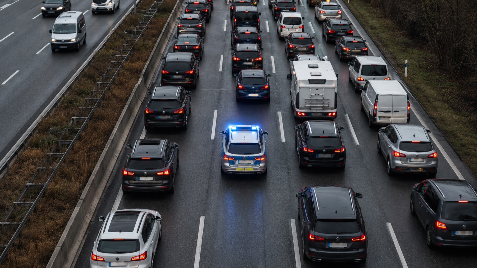 Luftbild einer deutschen Autobahn mit korrekt gebildeter Rettungsgasse, durch die ein Streifenwagen faehrt